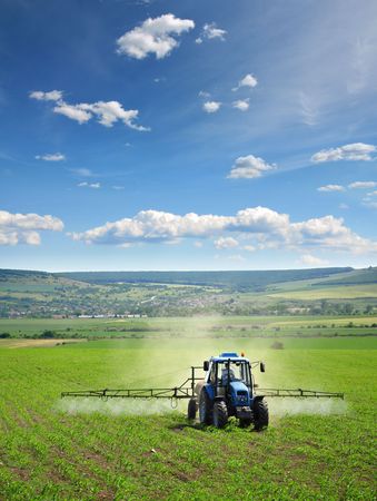 Farming tractor plowing and spraying on fieldの写真素材