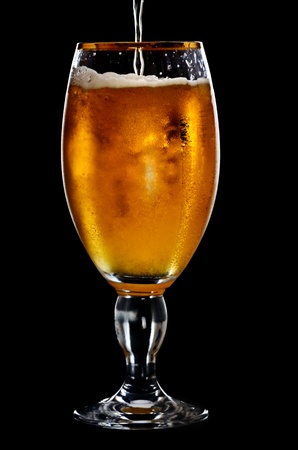 Beer into glass on a black backgroundの写真素材