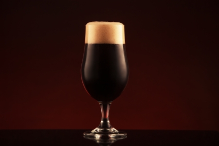 Glass of dark beer on brown background の写真素材