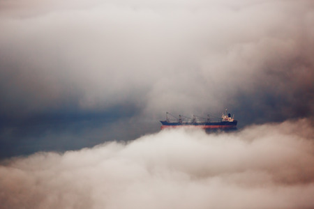 Cargo ship sailing in water of cloudsの写真素材