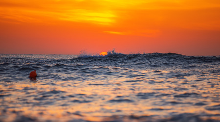 Sunrise and shining waves in oceanの写真素材