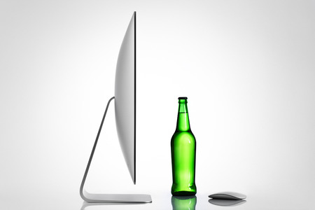 Isolated computer and beer bottle on a white background