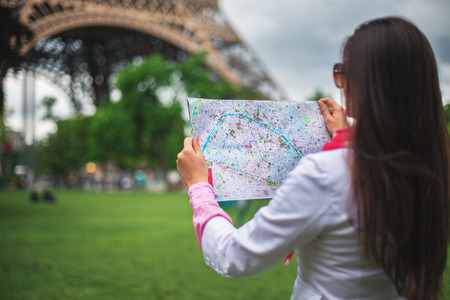 Confused young girl holding city Maps in Tuileries garden Paris, Franceの写真素材