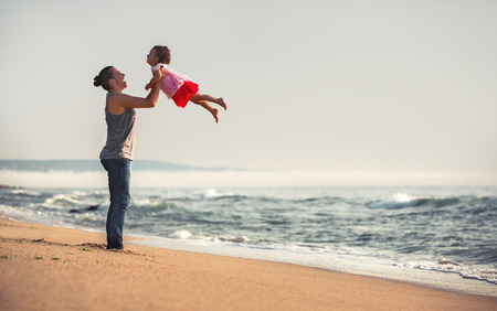 Mother and baby playing on the beach at the sunset timeの写真素材