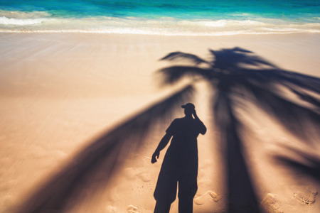 Man and palm tree shadows on tropical exotic beachの写真素材