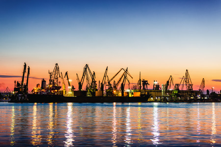 Silhouette of portal cranes in harbor on sunsetの写真素材