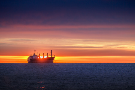 Sunrise over the sea with sailing cargo shipの写真素材