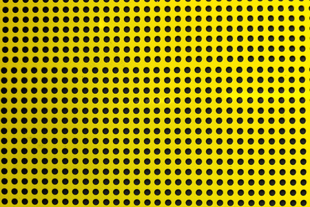 Yellow hole metal texture over a black background (selective focus, photographed with shallow DOF)の写真素材