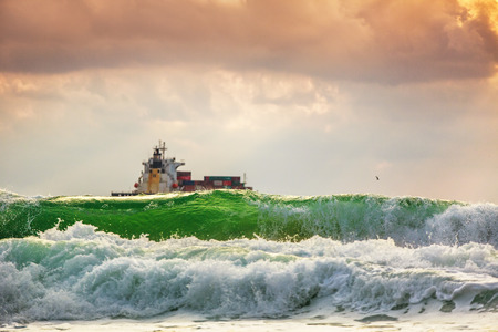 Sun setting at the sea with sailing cargo ship, scenic viewの写真素材