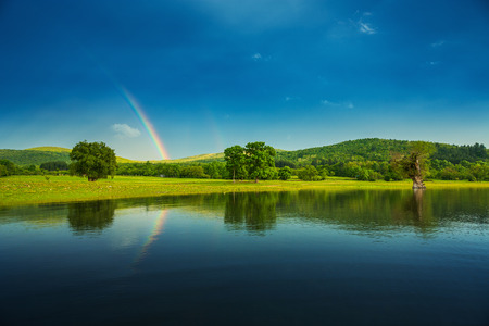 Rainbow over a lake, reflected in the water.の写真素材