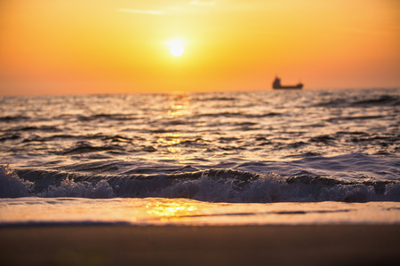 Sun setting at the sea with sailing cargo ship, scenic viewの写真素材