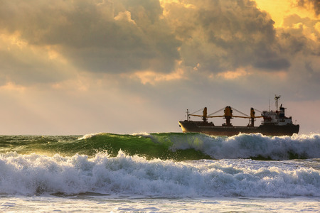 Sun setting at the sea with sailing cargo ship, scenic viewの写真素材