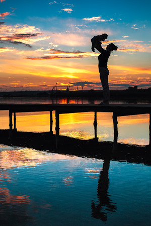 Mother and little baby having fun at sunsetの写真素材