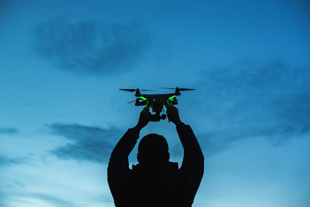 Man holding a drone for aerial photography. Silhouette against the sunset sky