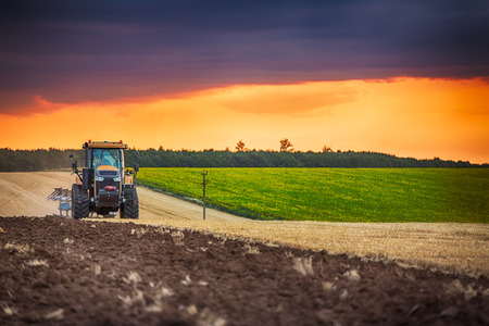 Farmer in tractor preparing land with seedbed cultivatorの写真素材