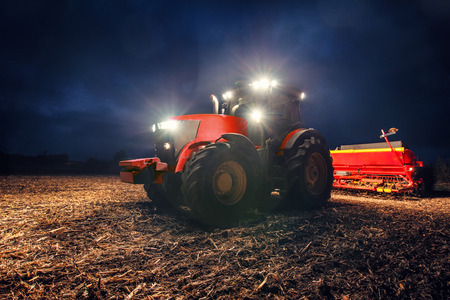 Tractor preparing land with seedbed cultivator at nightの写真素材