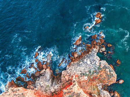 Aerial view of rocky coastline with crop fields and crashing ocean wavesの写真素材