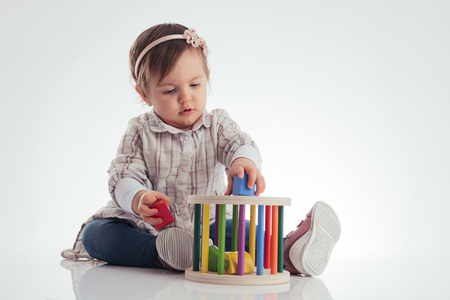 Cute baby girl playing wooden cubes isolated on white background.の写真素材