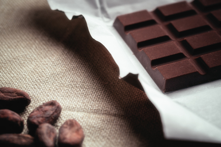 Dark chocolate and Raw cocoa beans. Background texture of old juteの写真素材