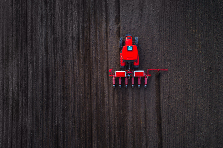 Aerial view of tractors working on the harvest fieldの写真素材