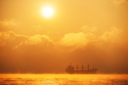 Sunrise over the sea with sailing cargo ship,. Transportation. Logistics. Shipping.の写真素材