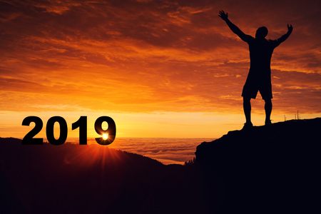 Man silhouette on the mountain top watching the sunrise and 2019 years while celebrating.の写真素材