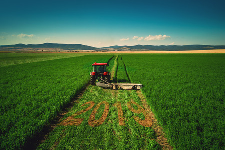 Tractor mowing green field, aerial view.の写真素材