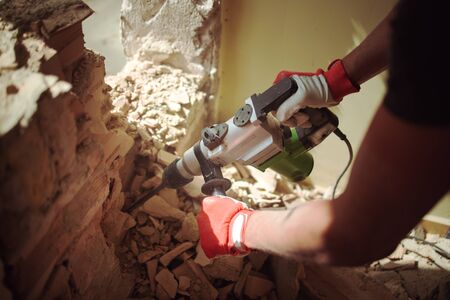 Home Renovation, Builder with hammer breaking wall indoorsの写真素材