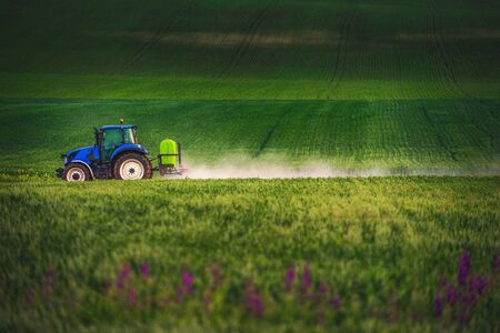 Farming tractor plowing and spraying on field.の写真素材