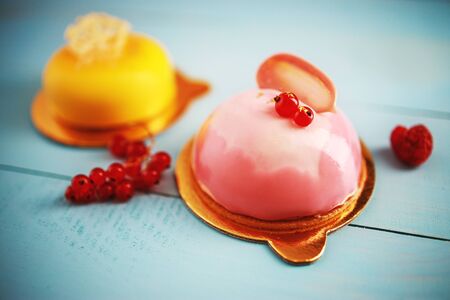 Mousse cake with strawberry puree, cream and fresh fruits on wooden blue background