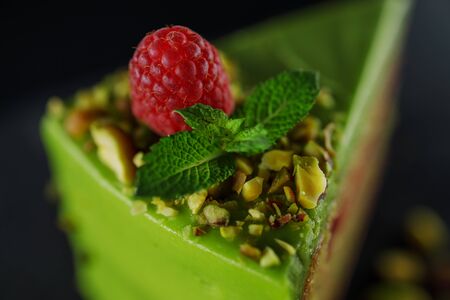 Cake with fruity cream and pistachio decorated with nuts, isolated on wooden background.の写真素材