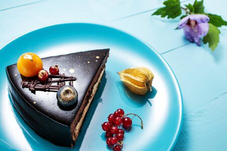 Chocolate cake with decoration and fruits on blue wooden background.の写真素材