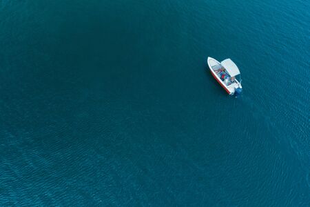 Aerial view of beautiful blue sea water at hot summer day and sailing motorboat