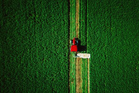 Tractor mowing green field, aerial view.