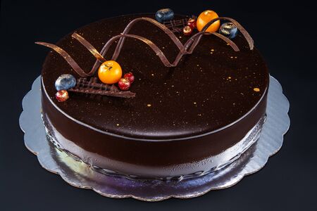 Chocolate cake with decoration and fruits as background.
