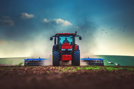 Farmer in tractor preparing land with seedbed cultivatorの写真素材