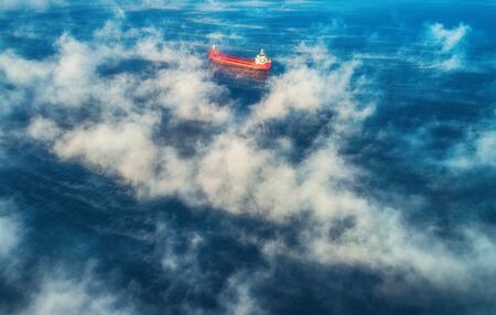 Aerial view of cargo container  ship sails in sea fog, crane vessel working for delivery of delivery containers.   の写真素材