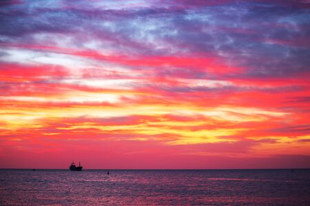 Sun setting at the sea with sailing cargo ship, scenic view