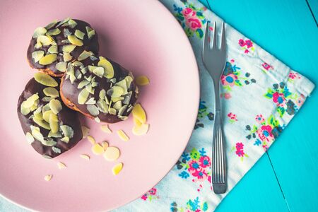 Homemade tasty eclairs in a plate with chocolate and nuts.