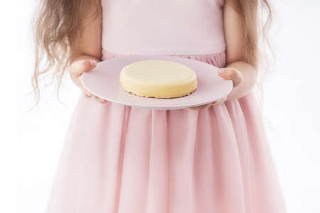 Beautiful little girl surprised from a tasty cheesecake. Kid ready to eat cake.