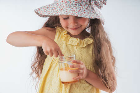 Beautiful little girl eating tasty cream dessert portrait isolated on white backgroundの写真素材
