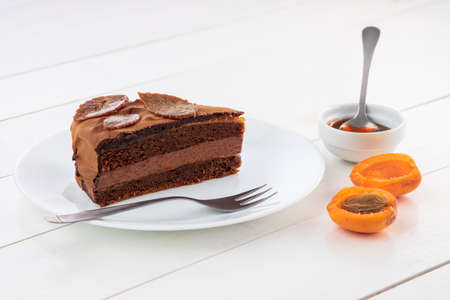 Piece of chocolate homemade cake with nuts and apricot jelly in a plateの写真素材