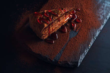 Piece of chocolate homemade cake with nuts and apricot jelly in a stone plateの写真素材
