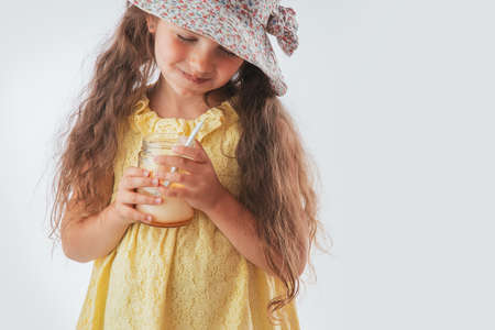 Beautiful little girl with spoon in mouth eating tasty cream. Eating yummy ice cream is funの写真素材