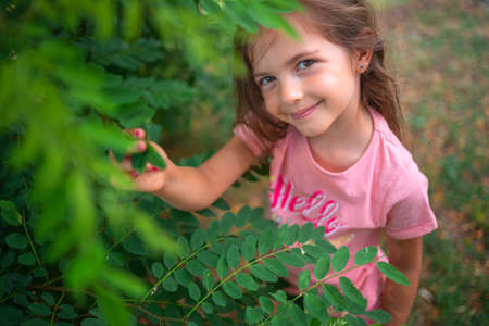 Little smiling girl playing with spring leaves in a parkの写真素材