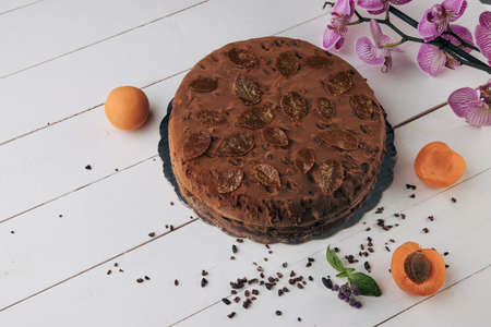 Chocolate homemade cake with nuts and apricot jelly on wooden backgroundの写真素材