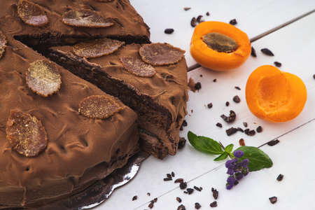 Chocolate homemade cake with nuts and apricot jelly on wooden backgroundの写真素材