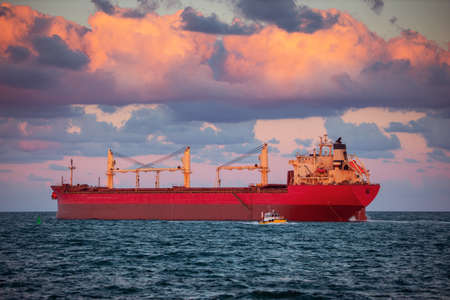 Sun setting at the sea with sailing cargo ship, scenic viewの写真素材