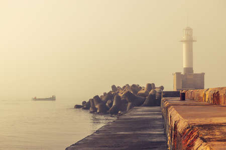 Sea sunrise. Foggy morning over the harbour and sailing fishing boatの写真素材