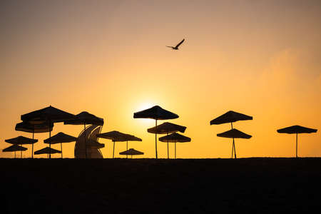 Sunrise with sunshade and life guard station silhouetteの写真素材